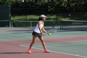 First doubles player and junior Isabelle Zhou prepares to serve.